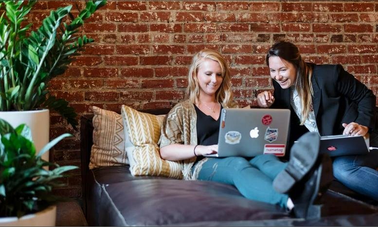 Spacious lounge at Tower Bridge, 1 St. Katharine Docks with brick walls, leather sofa, and lush indoor plants.
