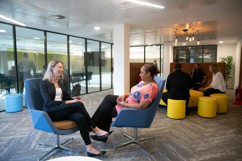 Bright breakout space at Tower Bridge Business Centre with colorful blue and yellow seating and glass walls.