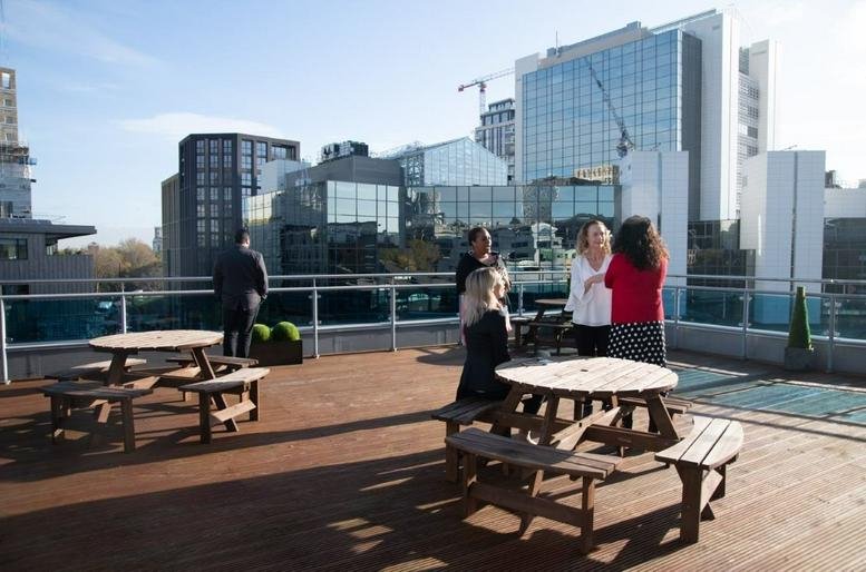 Spacious rooftop terrace at Tower Bridge Business Centre with picnic tables and modern city skyline views.