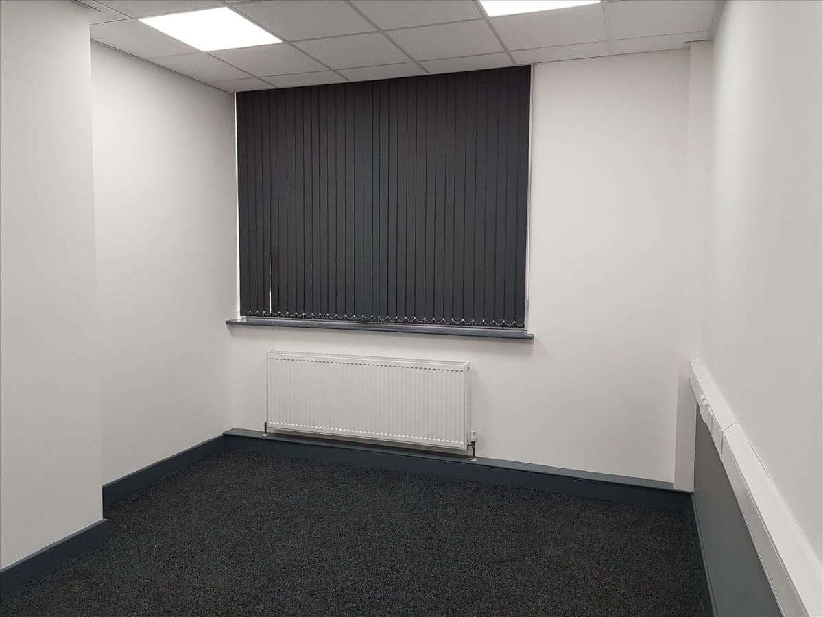 Spacious private office at Tradeforce Building with dark carpet and vertical window blinds.