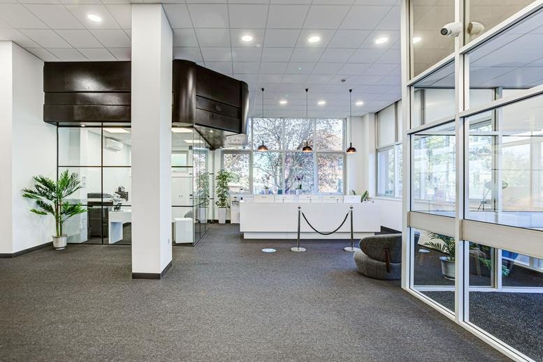 Spacious reception area at Trident Court, 1 Oakcroft Road with a white front desk and glass partitions.