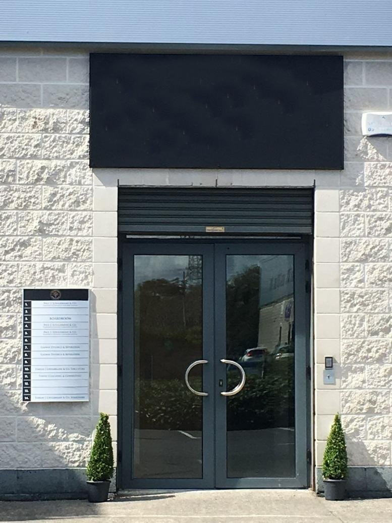 Exterior entrance of Unit 28 Orchard House with gray doors and small potted trees.