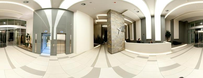 Spacious panoramic lobby with a polished stone reception desk and sleek elevators.