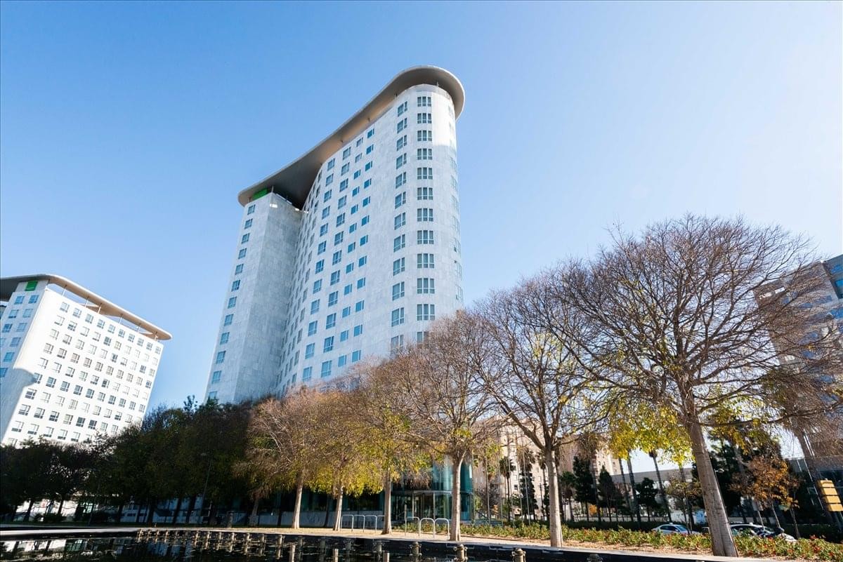 Low-angle exterior view of the modern curved high-rise building at Valencia Sorolla Center.