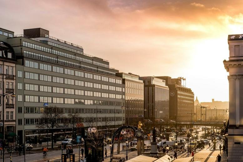Exterior view of the tiered facade at Vasagatan 16 under a golden sunset.