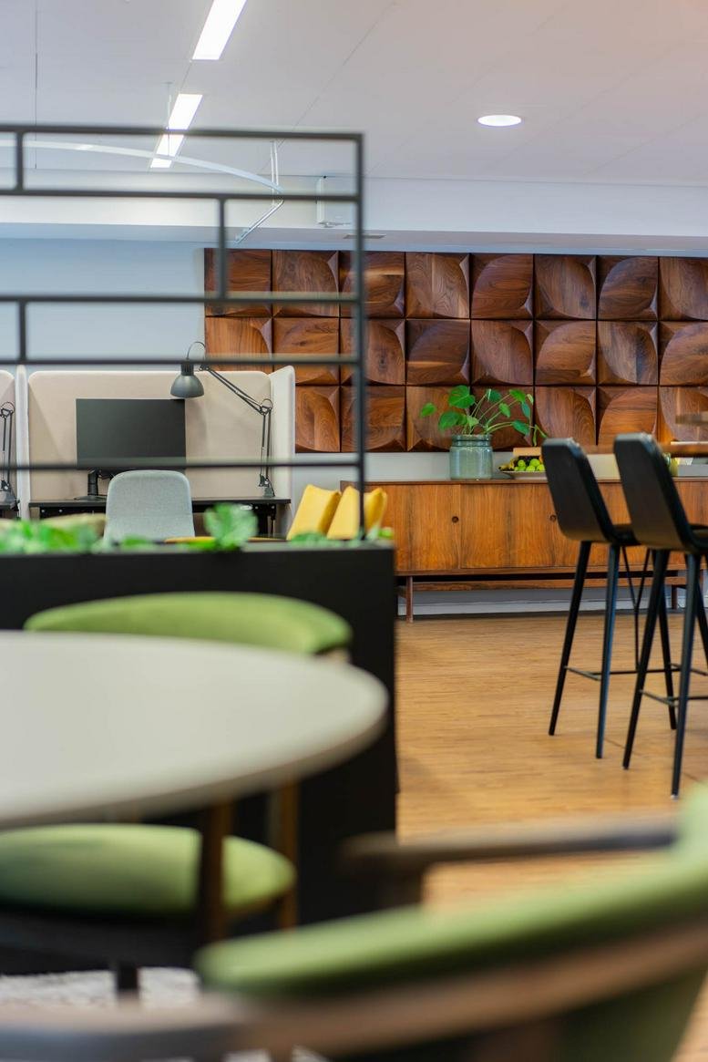 Spacious communal lounge at Vasagatan 7 featuring a wooden feature wall and green chairs.