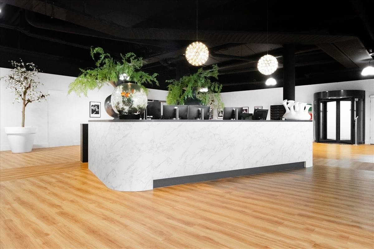 Sleek marble reception desk at Claudius Prinsenhof with warm wood flooring and potted plants.
