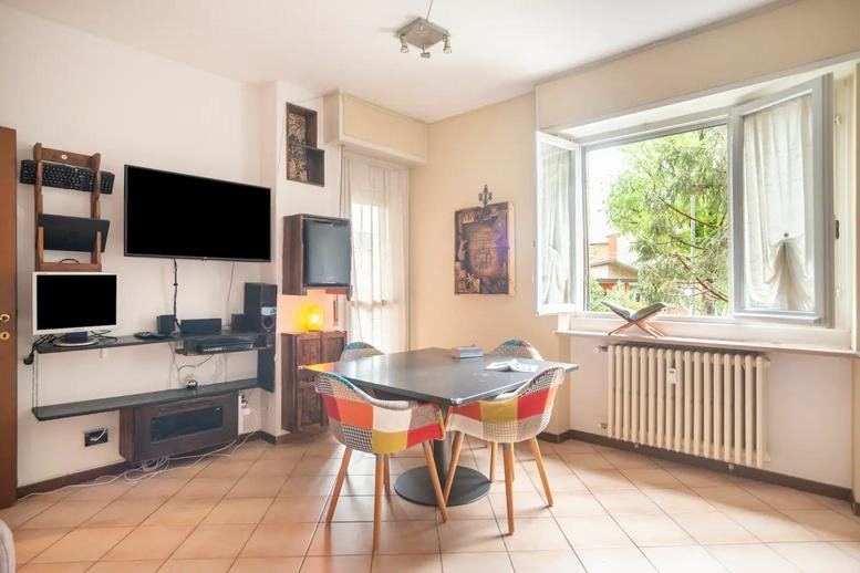 Dining area with a sleek black table and patchwork chairs near a large window.
