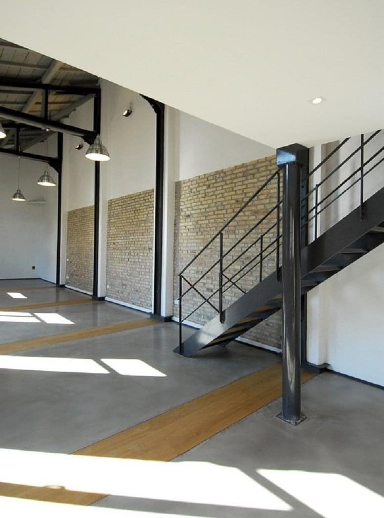 Spacious communal area featuring polished concrete floors and exposed brick accent walls.