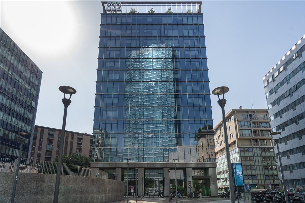 Exterior view of the glass-facade building at Via Filippo Sassetti, 32, Milan.