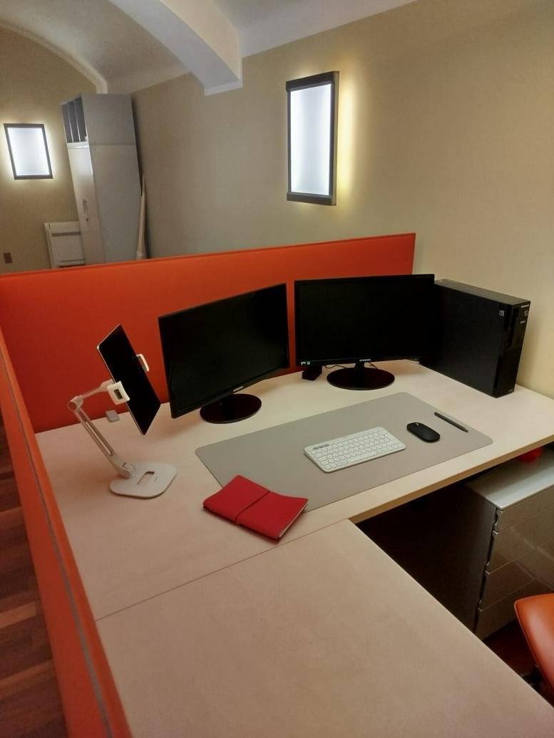 Modern desk setup with multiple screens and a tablet in a bright office environment.