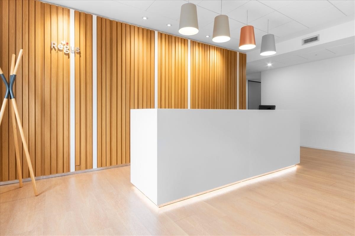 Reception area at Via Libero Temolo 4 featuring a white desk against a vertical wood-slat wall.