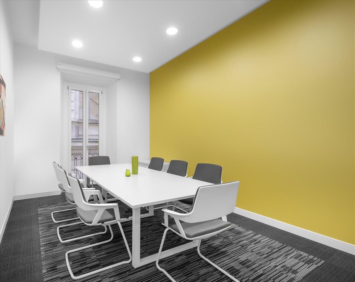 Professional meeting room at Via Mengoni 4, 20121 Milan featuring a yellow accent wall.