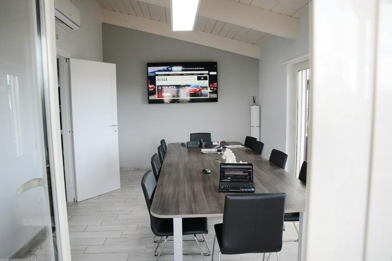 Professional meeting room at 149 Via Piano del Principe with a large wood-finish table and wall-mounted screen.