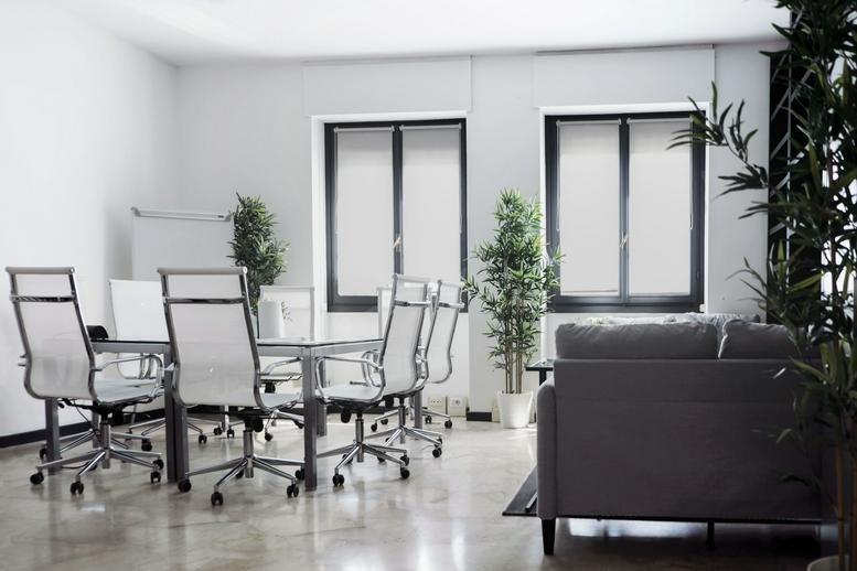 Meeting room at Via Sammartini 33, Milan, Italy with mesh chairs and large windows.
