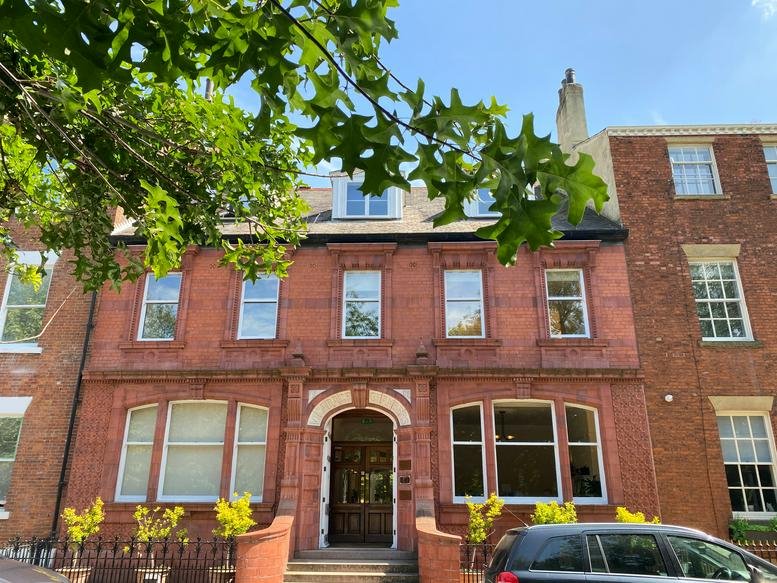 Exterior red brick facade of Vicarage Chambers, 9 Park Square East with arched entrance and green foliage.