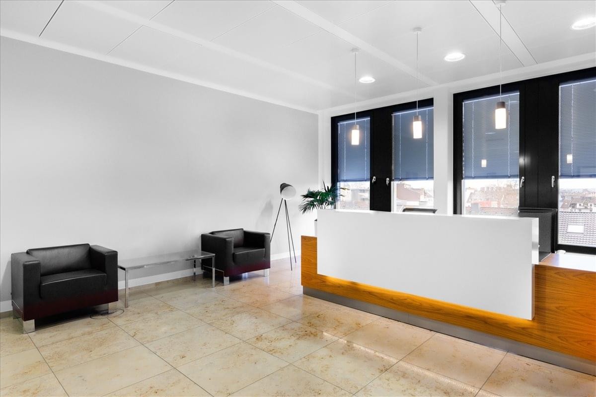 Professional reception area with a minimalist white desk and leather armchairs.