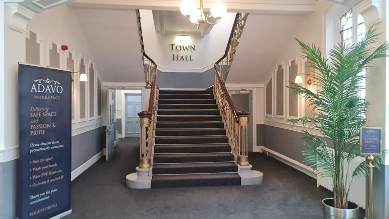 Grand entrance lobby of Wallsend Town Hall featuring a central staircase, ornate archways, and a large indoor plant.
