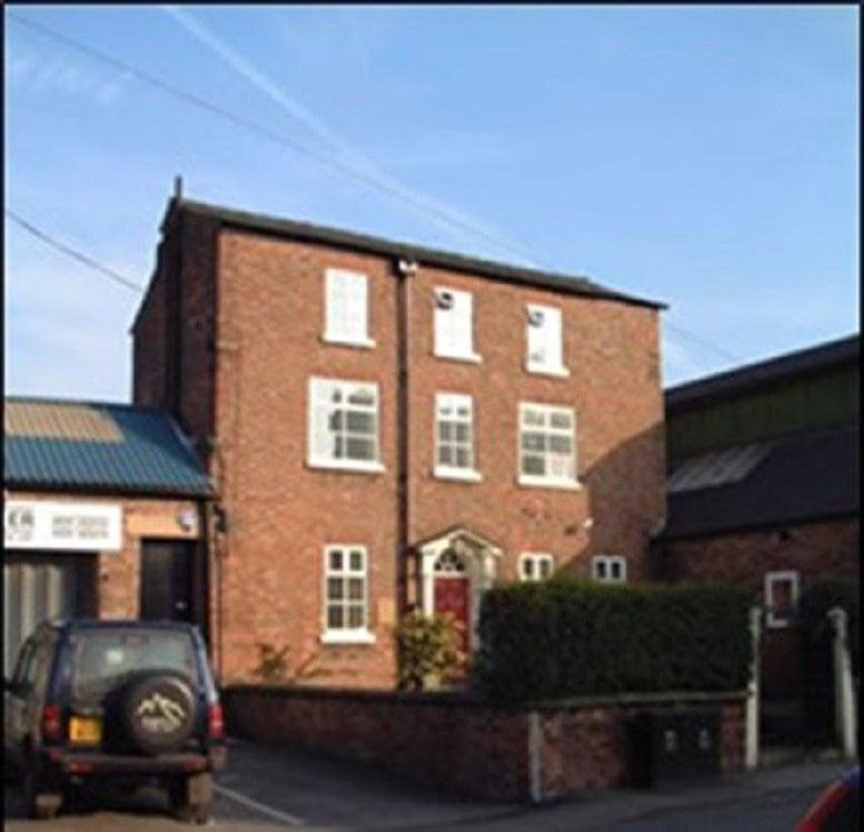 Three-story brick building facade with a central entrance and white window frames.
