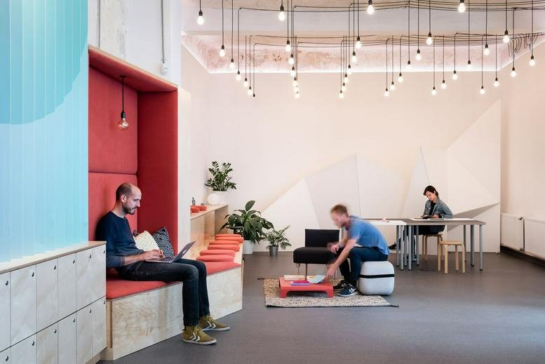 Spacious communal lounge at Liftoff, Weiner Leó utca 4 with red booth seating and designer pendant lights.