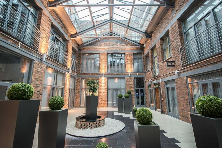 Spacious brick-walled internal courtyard of West Midlands House under a large glass atrium roof.
