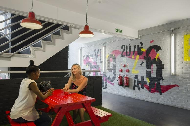 Vibrant breakout area featuring a red picnic table on artificial grass and colorful wall murals.