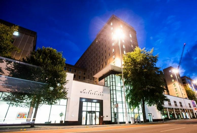 Exterior view of the Whitefriars Business Centre building at night with lit windows and glass entrance.