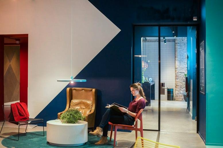 Spacious communal breakout area at Willem Ruyslaan 225 with a blue geometric wall and comfortable armchairs.