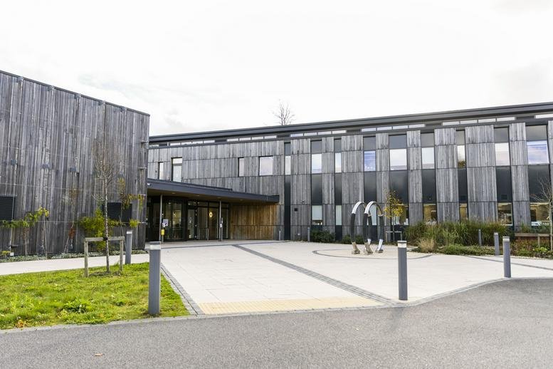 Ground-level facade of the Wood Centre for Innovation featuring modern timber cladding and a paved entrance.