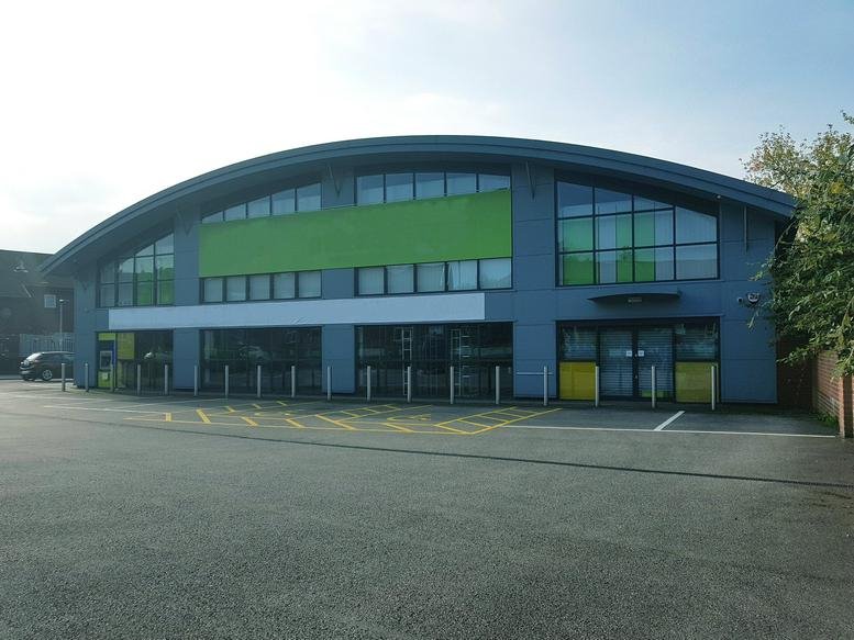 The arched exterior of Woodhouse Lane, Unit 2, Wigan, Greater Manchester with green accents and large windows.