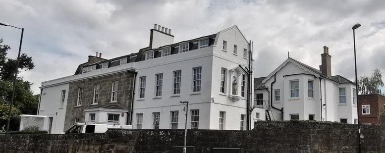 Exterior view of the white facade and stone building at Worth Corner, Turners Hill Road.