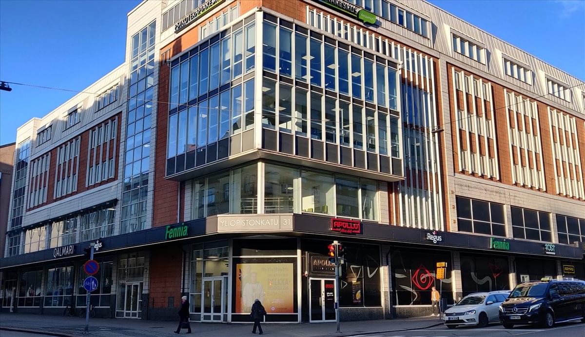 Modern exterior of the Yliopistonkatu 34 building with large glass windows and street-level shops.