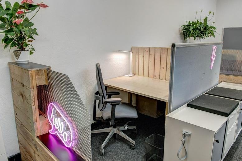 Spacious workspace at Ollenhauerstraße 15 with a wooden desk, ergonomic chair, and a pink neon sign.