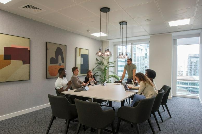 Spacious communal area at One Canada Square with team meeting around a white table and abstract wall art.