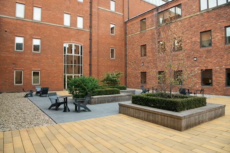 Private outdoor courtyard with brick walls, wooden decking, and modern patio seating.