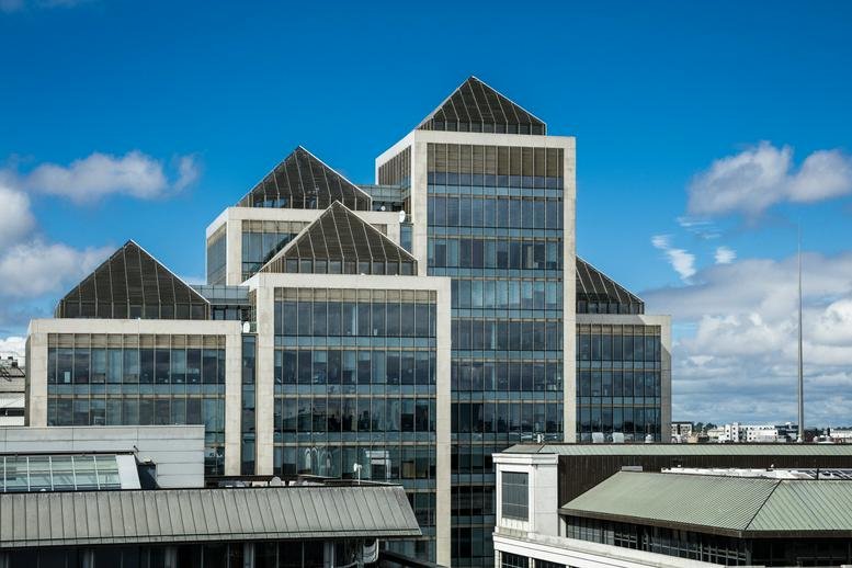 Exterior facade of One George’s Quay Plaza featuring glass panels and distinctive pyramid roof structures.