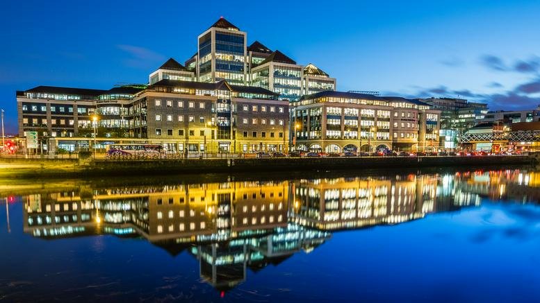Exterior view of the building at dusk with lights reflecting in the water.