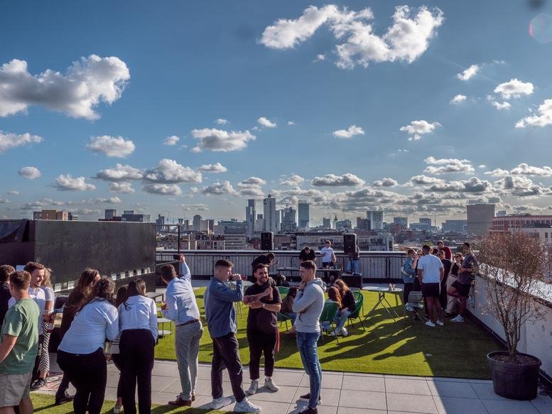 Rooftop terrace at One Silk Street with artificial grass, seating, and panoramic city skyline views.