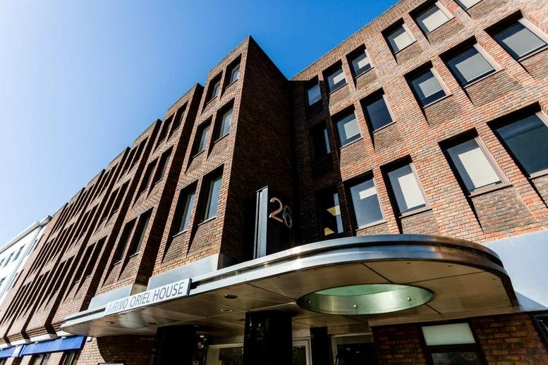 Exterior brick facade and entrance of Oriel House, 26 The Quadrant, Richmond under a clear blue sky.