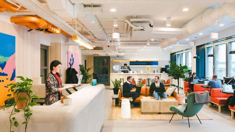 Spacious reception at Oskar-von-Miller-Ring 33 with a white curved desk, colorful wall art, and lush indoor plants.