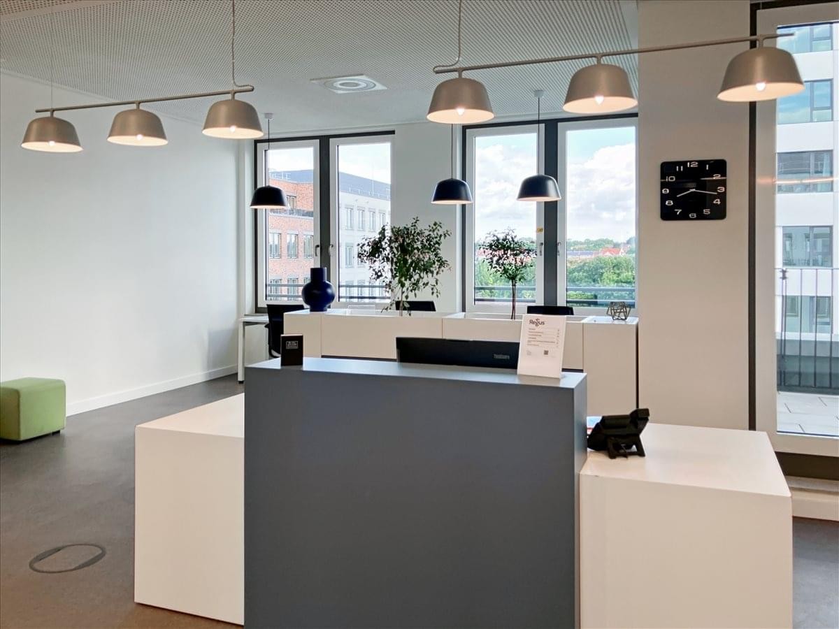 Modern reception area at Ostendstrasse 115 featuring a sleek grey and white desk and pendant lighting.