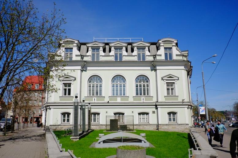 Exterior view of the historic white facade of Pärnu maantee 12, Tallinn with arched windows.