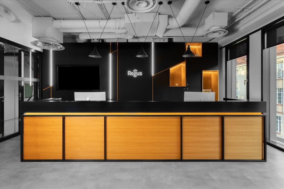 Sleek black and wood-paneled reception desk with exposed ceiling pipes.
