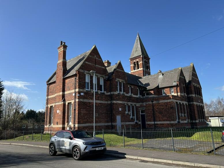 Exterior of The Clocktower Business Centre, a historic red-brick building with a prominent pointed tower.