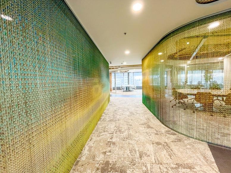 A vibrant hallway featuring a multicolored mesh feature wall at Paseo de la Castellana 85, Madrid.