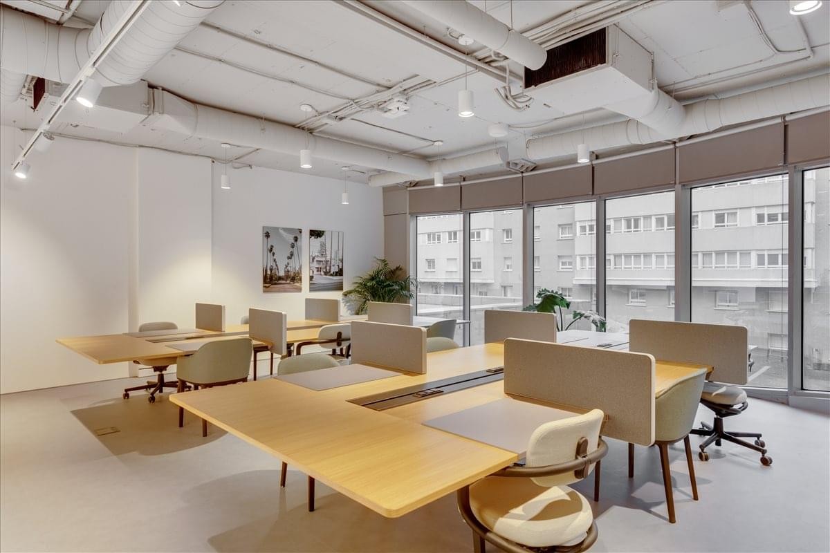 Spacious open-plan workspace at Paseo de la Castellana, 200, Madrid with wooden desks and industrial ceilings.