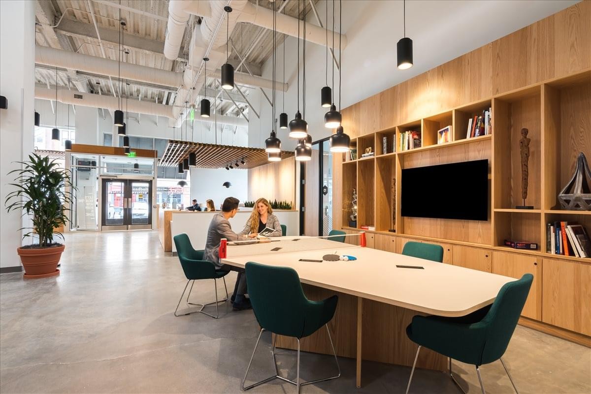 Spacious communal area at Paseo de la Castellana, 81, Madrid with light wood shelving and green armchairs.