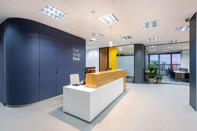 Bright reception area with a white and wood desk and navy blue feature wall.