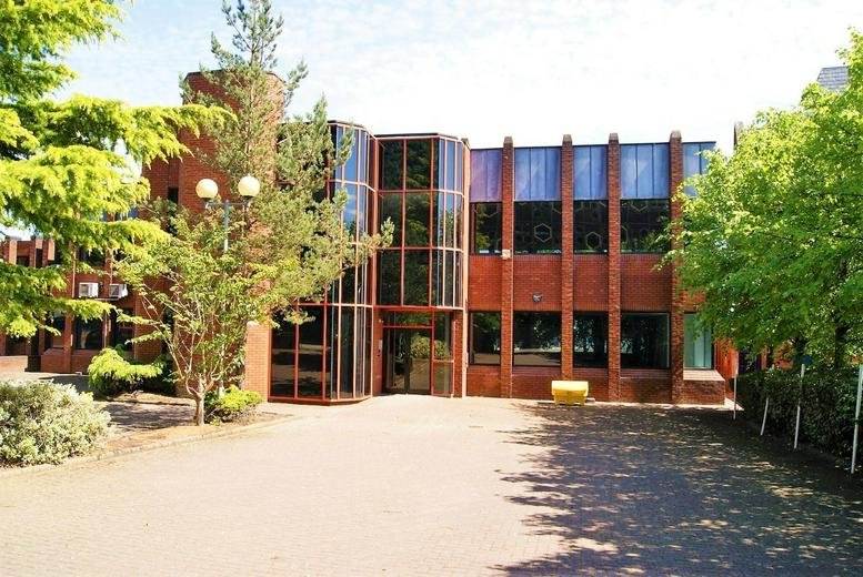 The brick and glass exterior of Patten House, Moulders Lane, Warrington with surrounding green trees.
