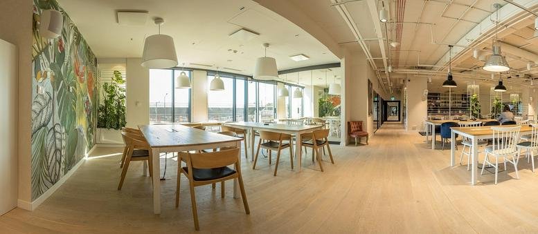 Wide-angle communal area at Pawia 9 Street with dining tables and botanical wall art.